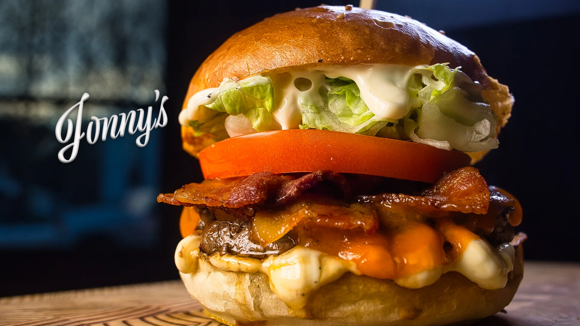Delicious bacon cheeseburger with fresh toppings on a wooden table.