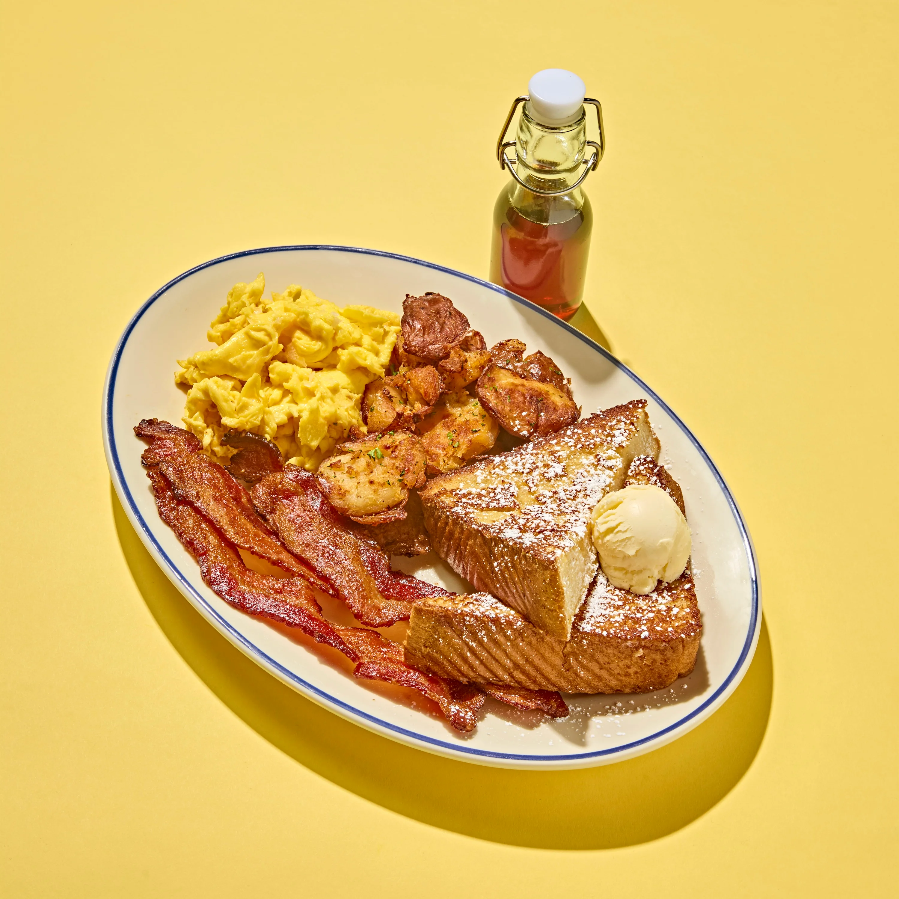 Classic American breakfast platter with French toast, scrambled eggs, bacon, and potatoes