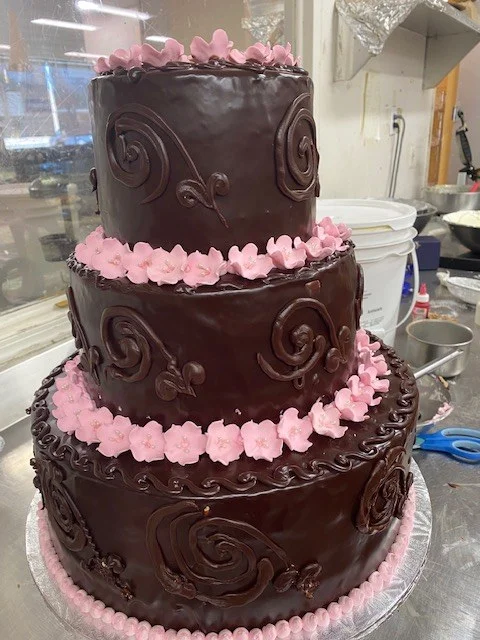 Three-tier chocolate cake with pink piped flowers from The Kosher Pastry Oven