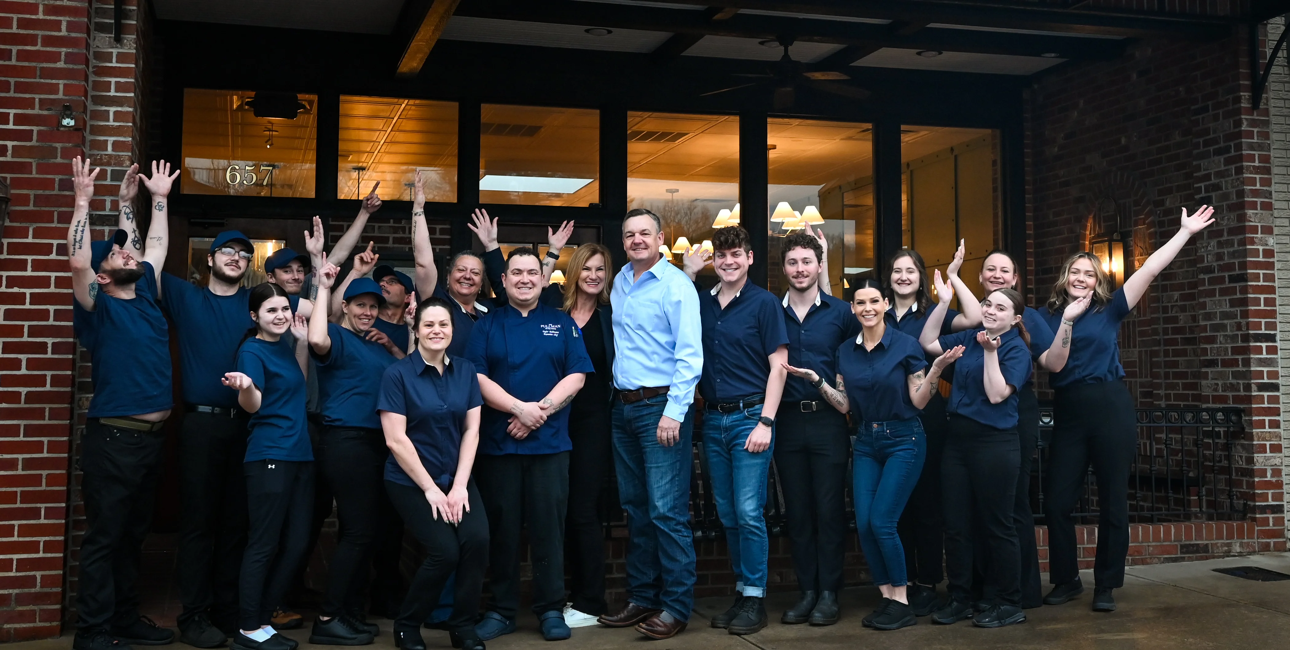 Cheerful restaurant staff posing outside The Pullman All-Day Eatery