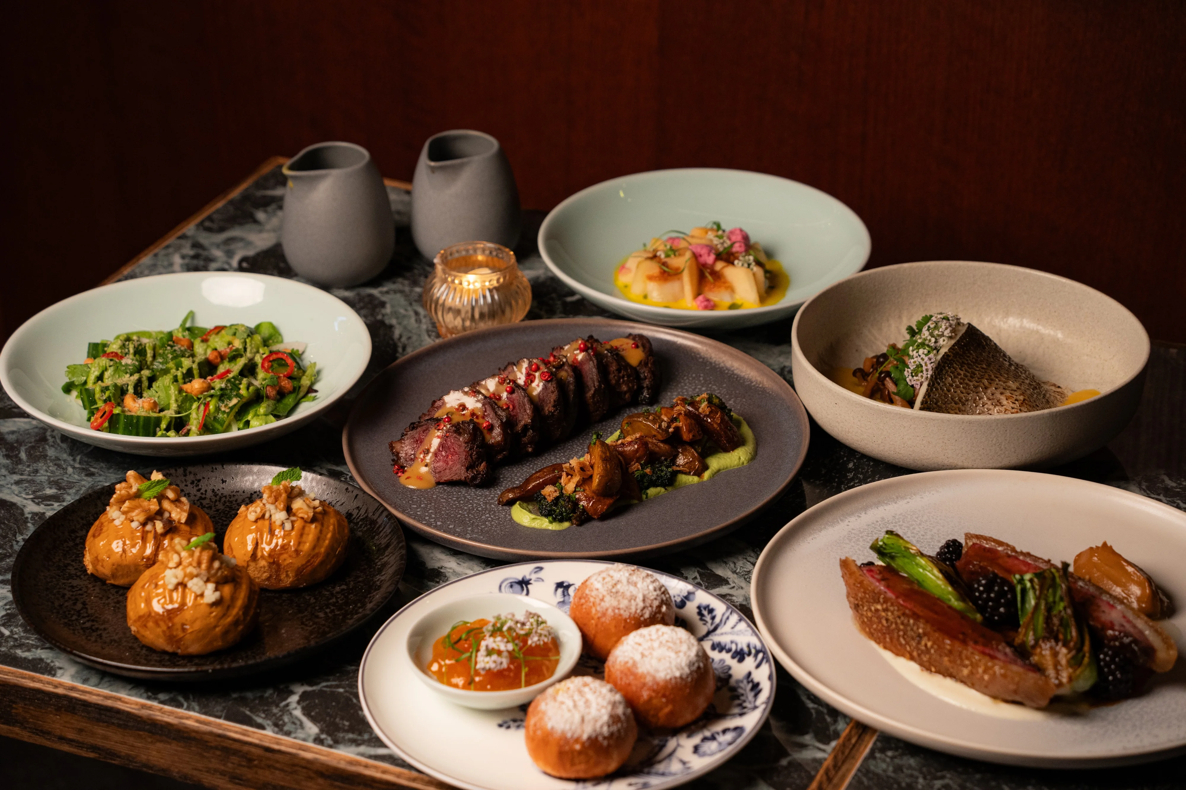 Artfully plated modern Asian dishes including grilled meats and desserts