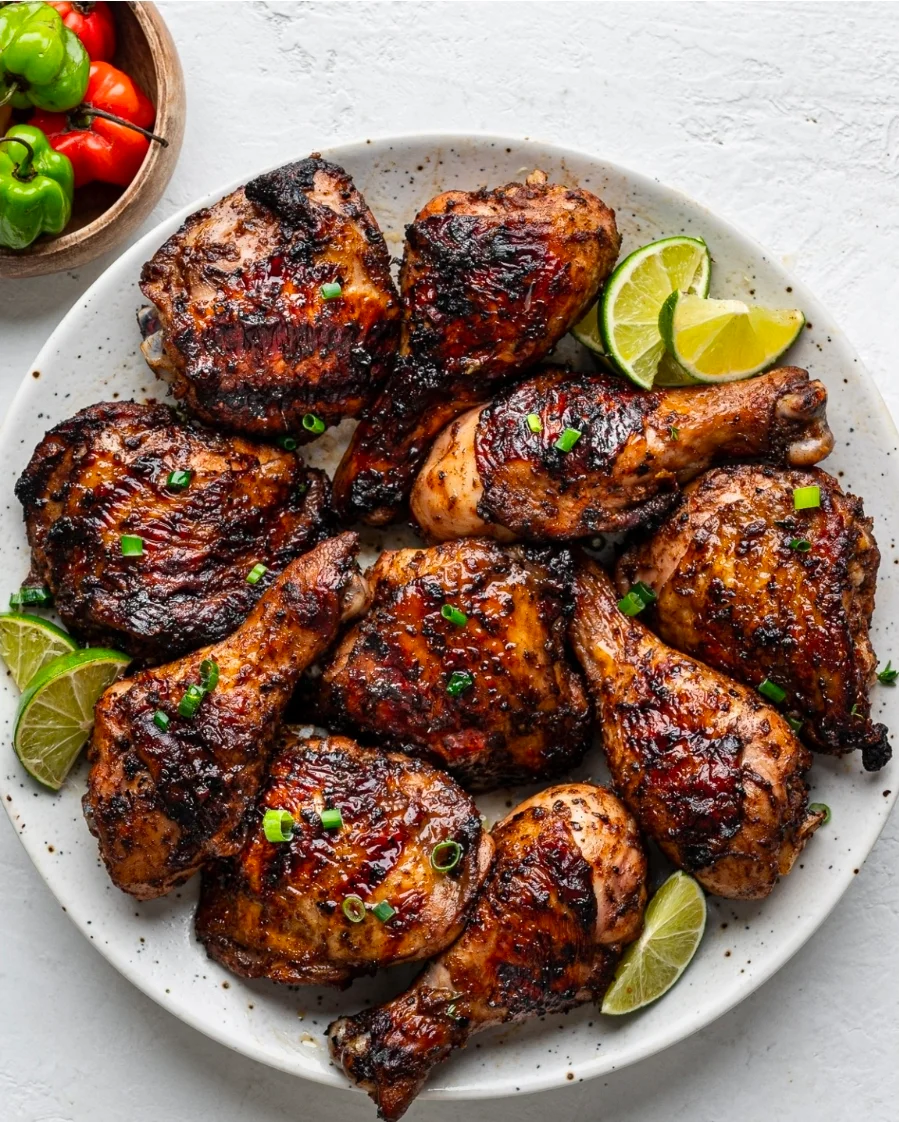 Grilled chicken drumsticks garnished with lime and green onions on a plate.
