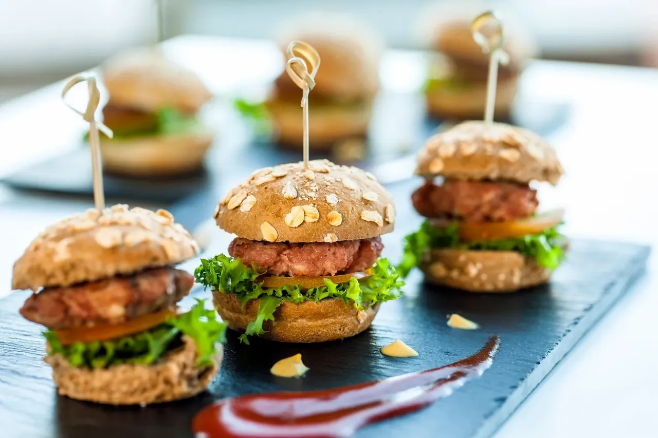 Miniature gourmet sliders on a slate platter