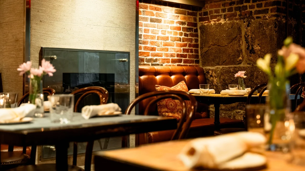Upscale restaurant dining room with exposed brick and leather banquette seating
