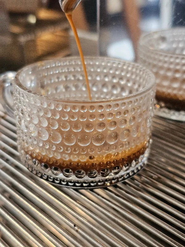 Pouring espresso into a textured glass cup