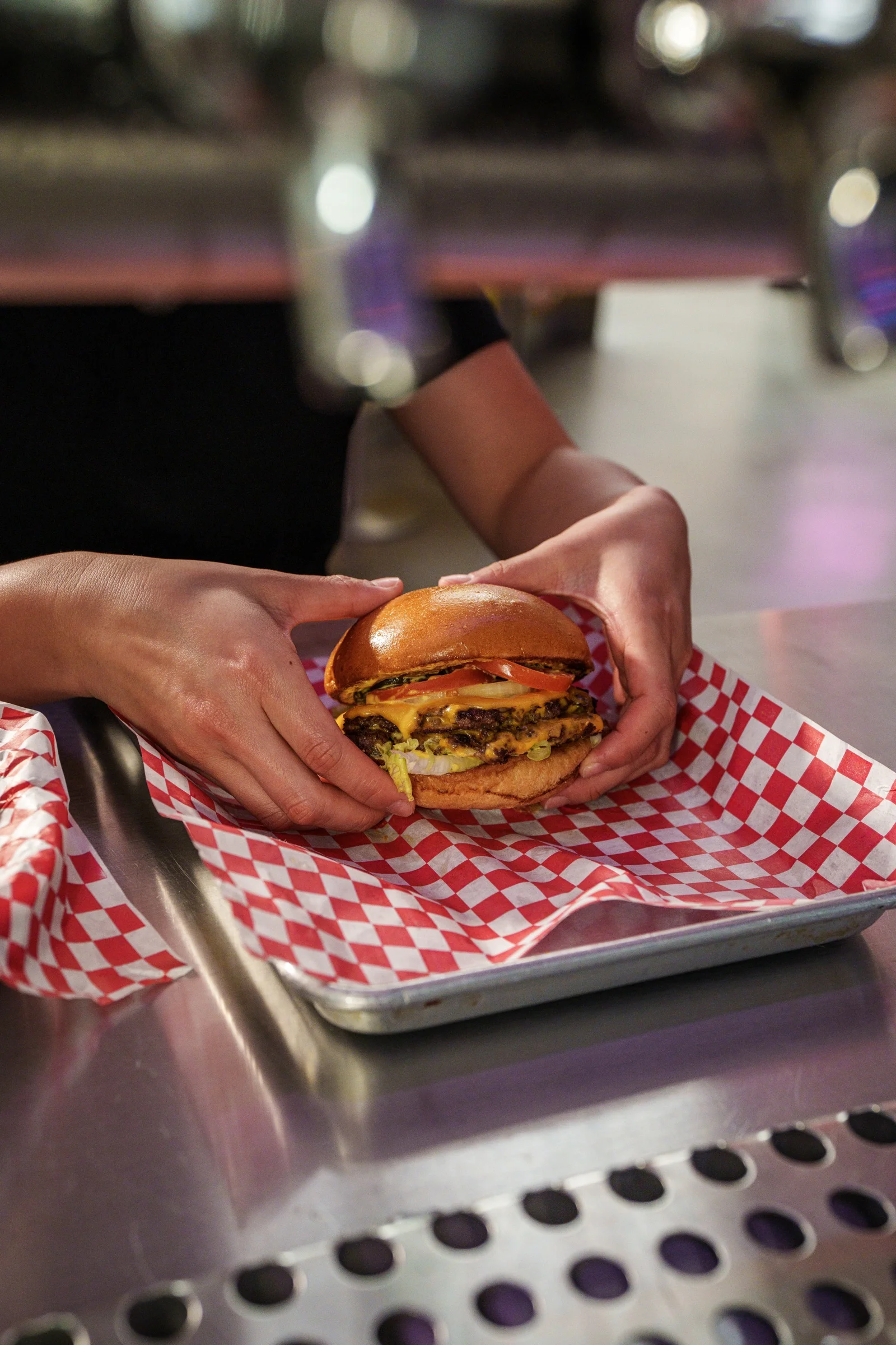 Juicy cheeseburger served on a tray with red checkered paper