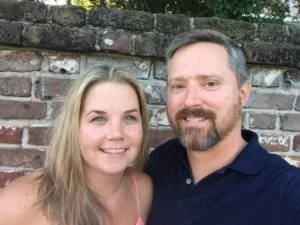 Couple smiling together in front of a brick wall