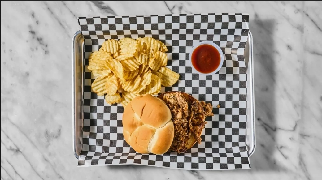 Pulled pork sandwich with chips and barbecue sauce