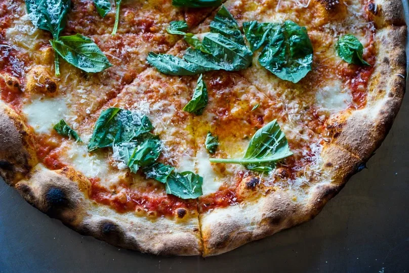 Margherita pizza topped with fresh basil leaves