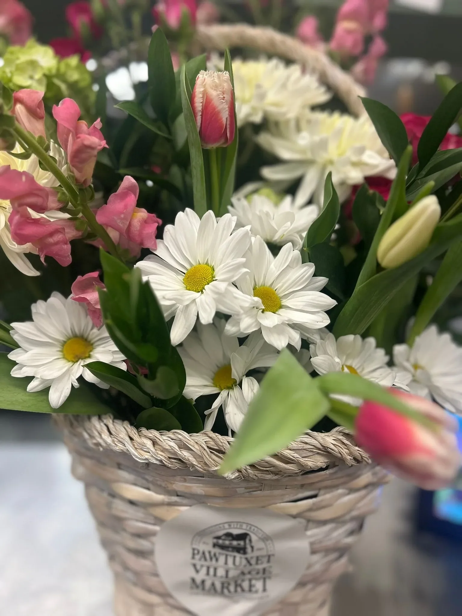 A beautiful custom floral arrangement from Pawtuxet Village Market featuring white hydrangeas and deep red roses in an elegant black basket.