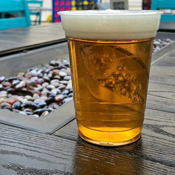 Chilled beer in a plastic cup on a wooden table