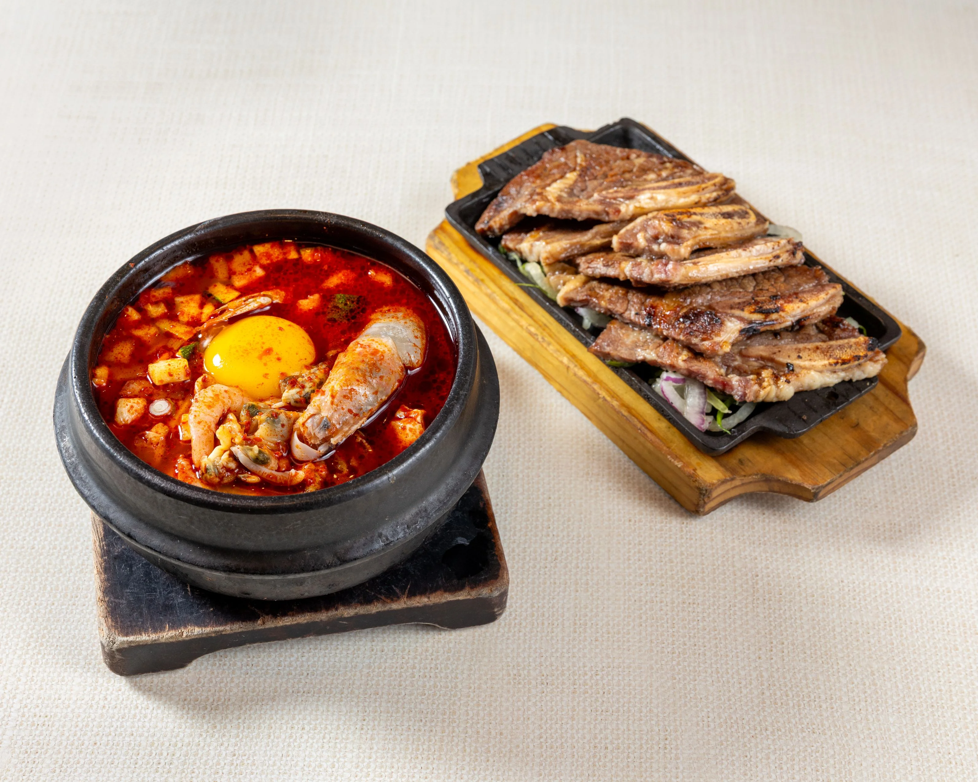 Korean spicy seafood stew with egg and grilled meat platter