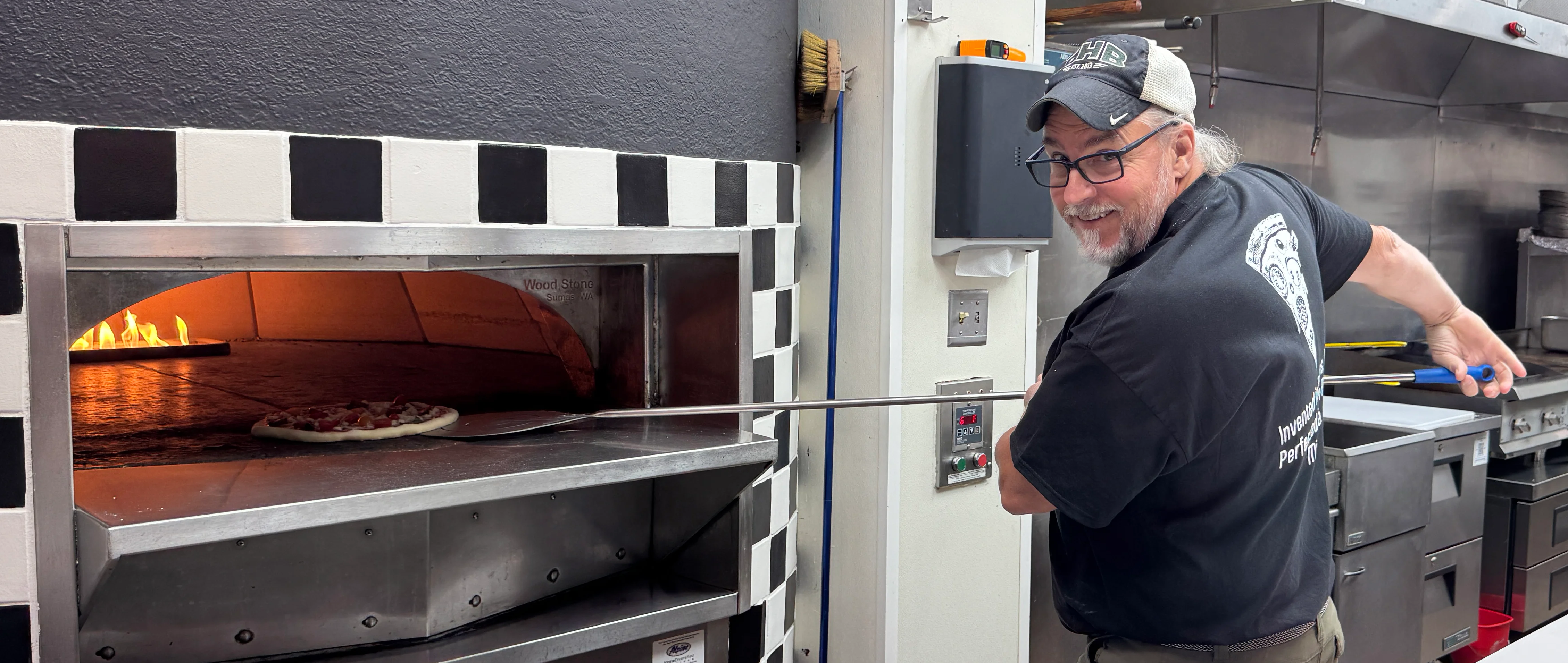An owner from the Hearth putting in pizza in a pizza oven