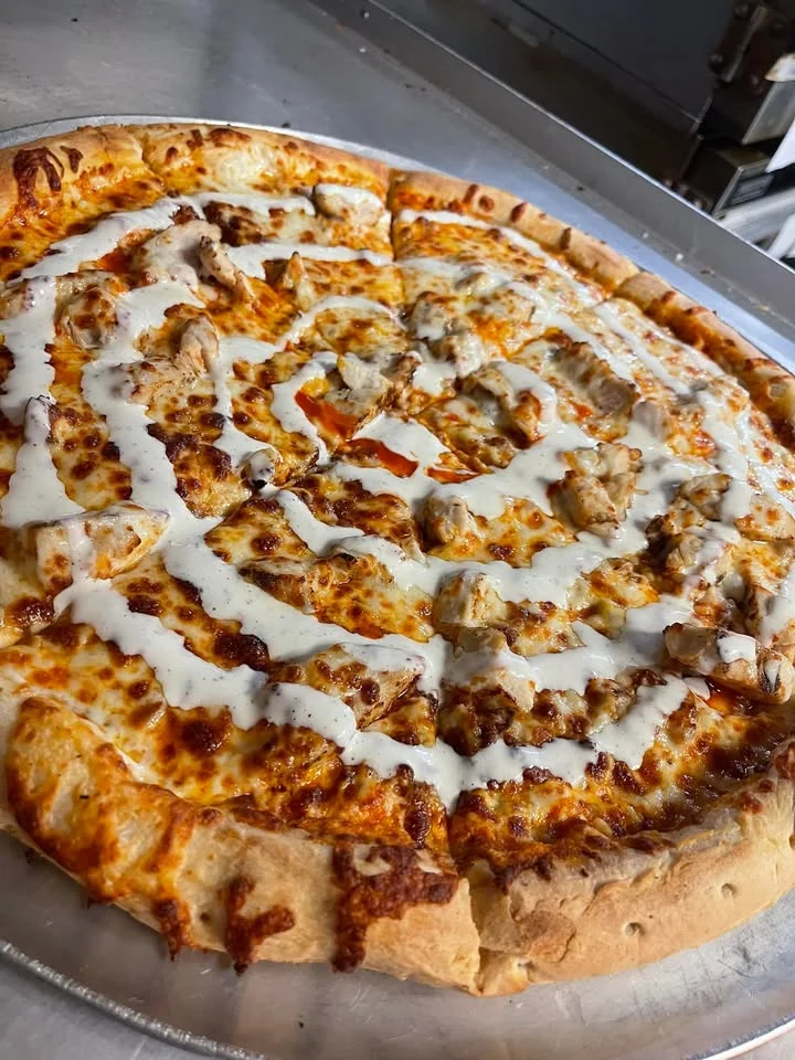A pizza topped with bits of chicken and barbecue sauce on a golden crust, showcasing melted cheese.
