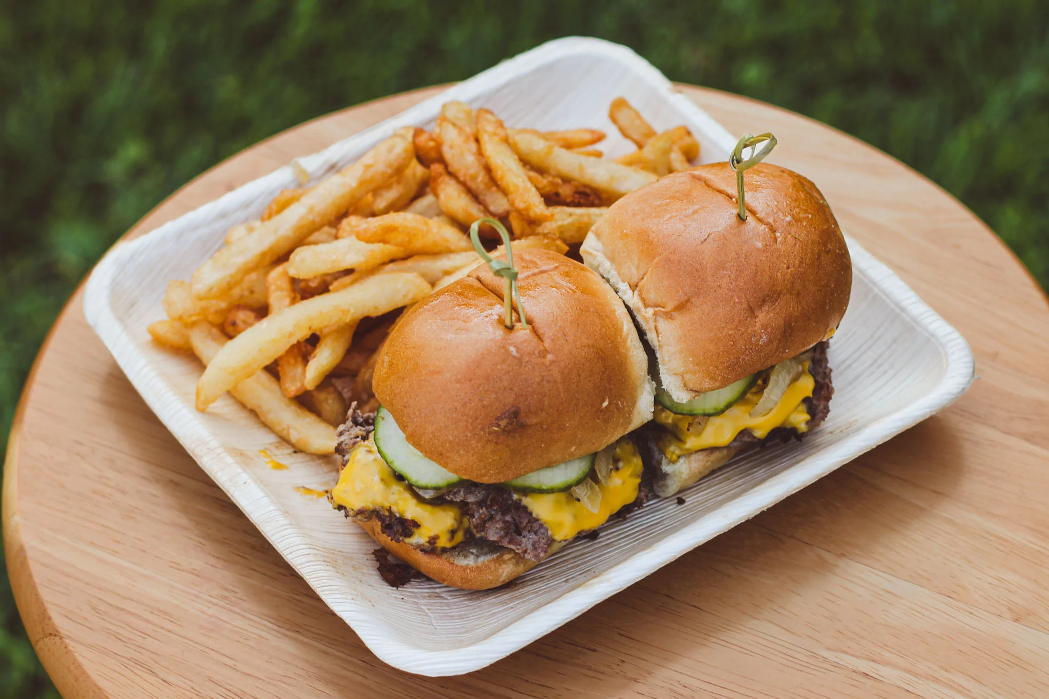 Classic American cheeseburger sliders with fries on a wooden table