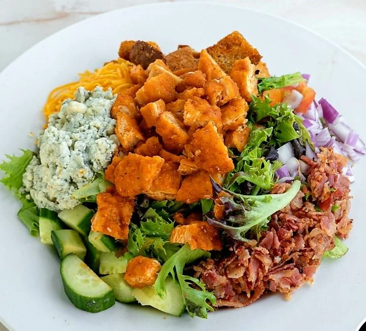 Buffalo chicken salad at Moonlite Diner with mixed greens, cucumbers, tomatoes, bacon, blue cheese, cheddar, croutons, and red onions.