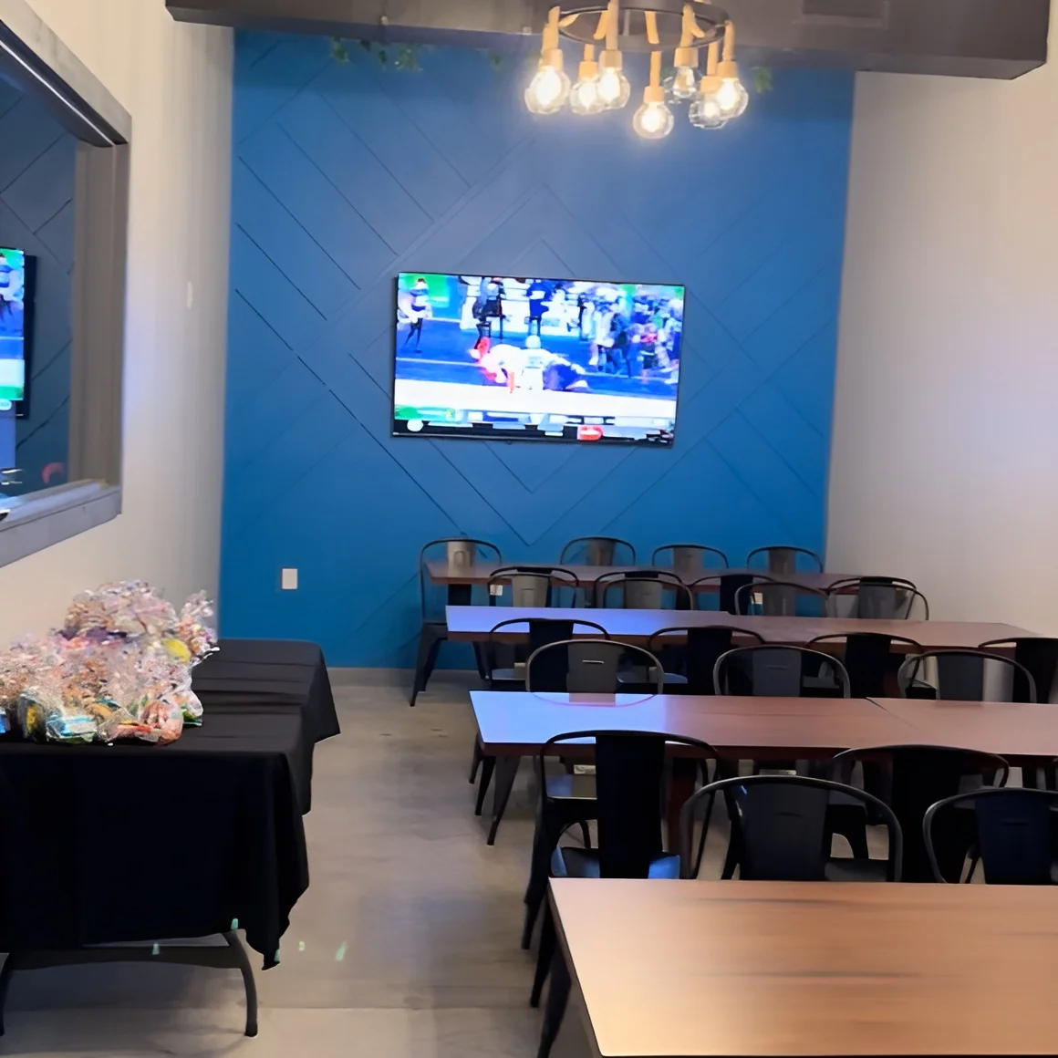 Interior of a restaurant with tables, TV, and decorative lighting.