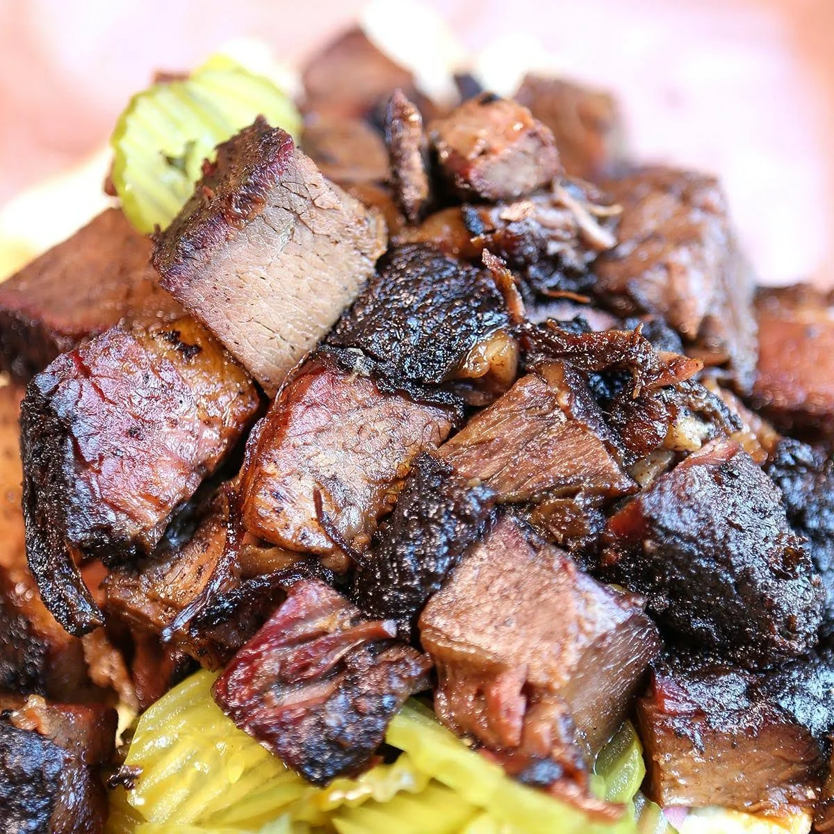 A close-up view of diced pieces of smoked beef, showcasing a rich, dark exterior with hints of seasoning and tenderness.
