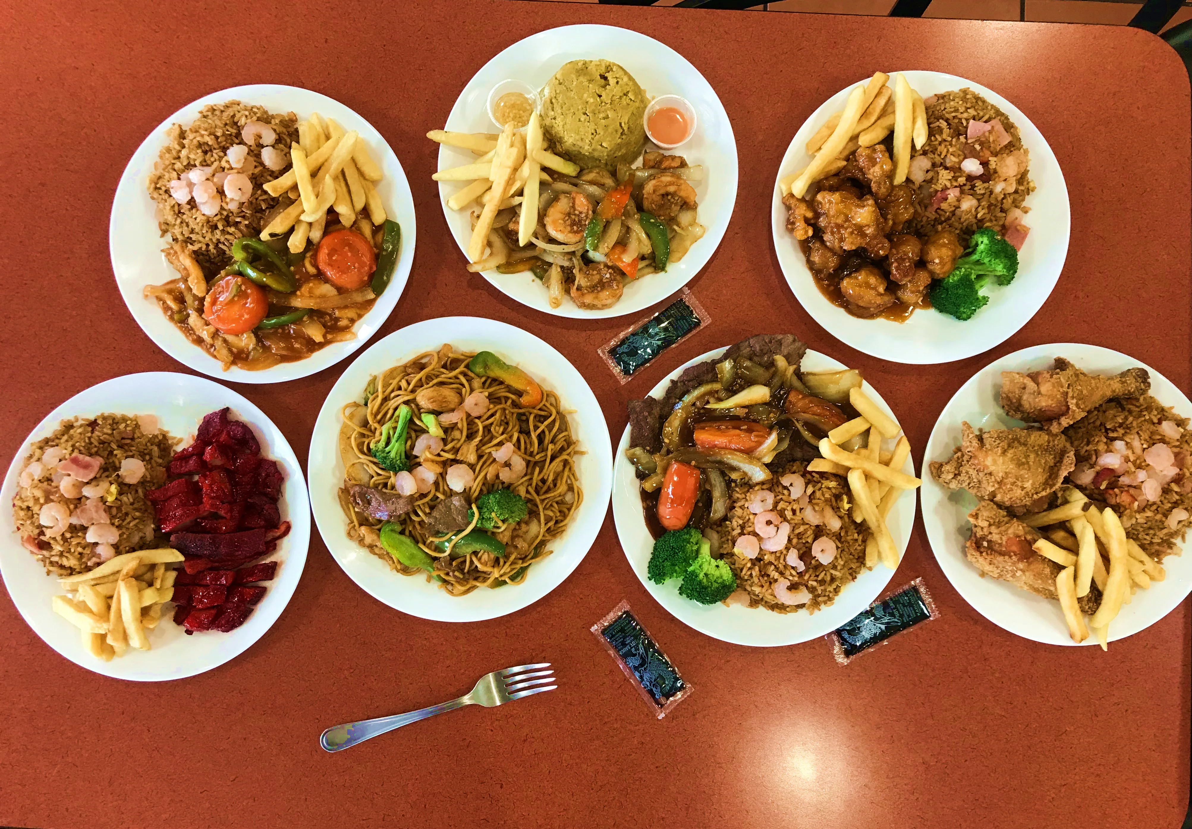 Assorted Chinese takeout dishes with rice, noodles, and fried chicken