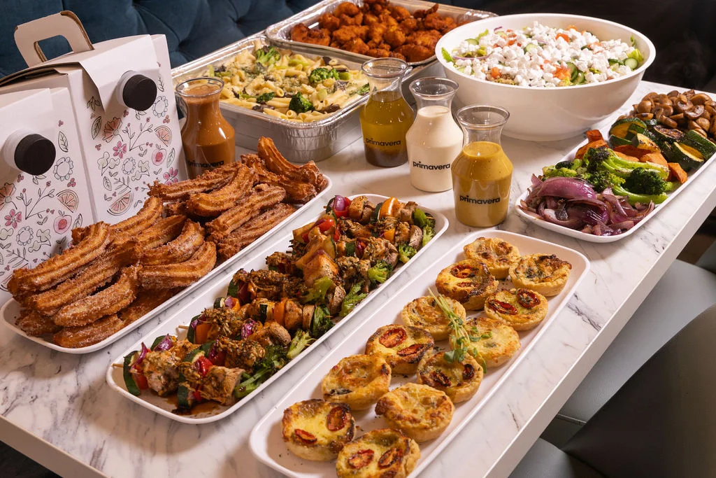 Assorted catering spread with churros, grilled skewers, and fresh salads