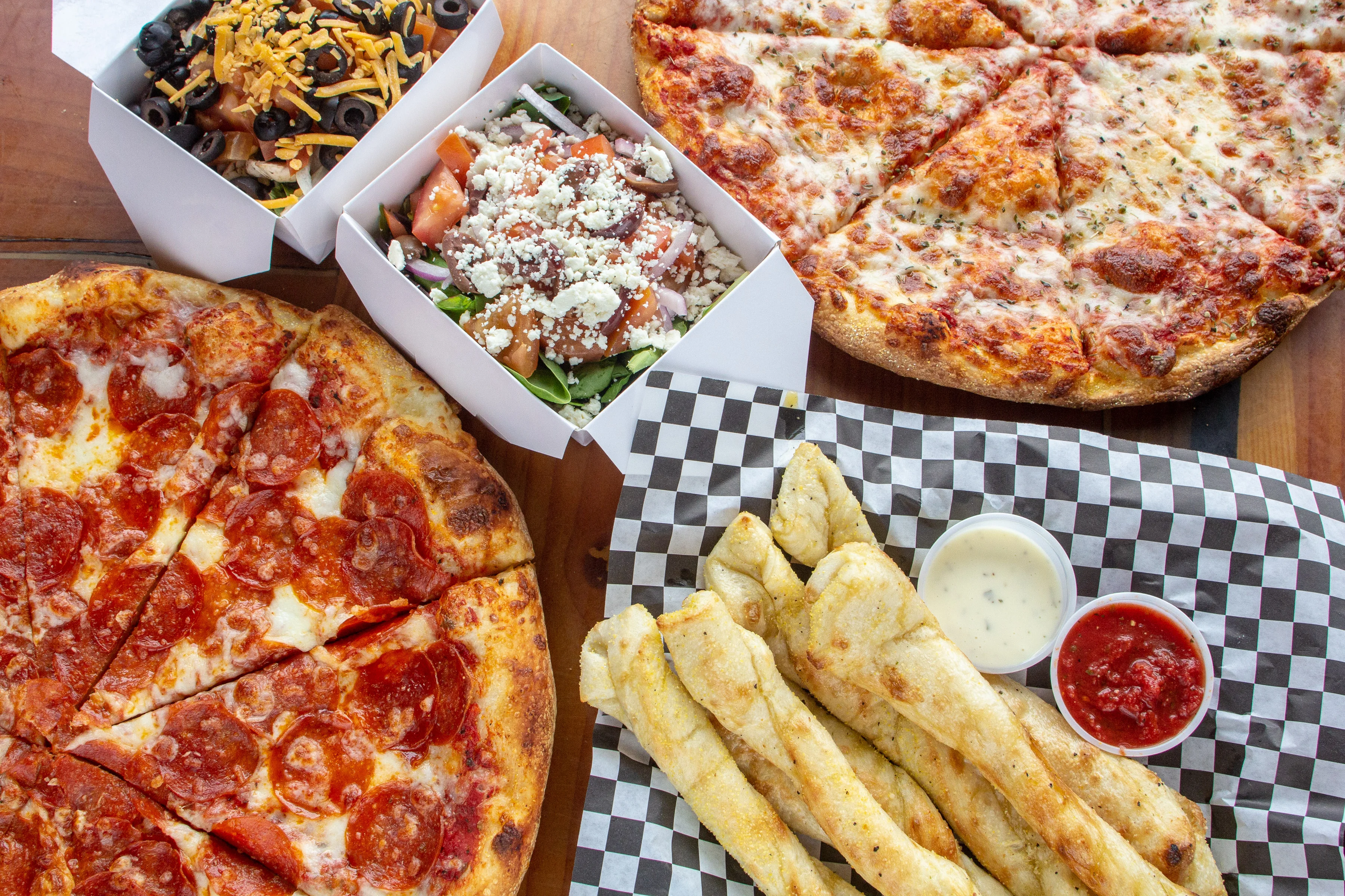 Pepperoni pizza and garlic breadsticks on a wooden table