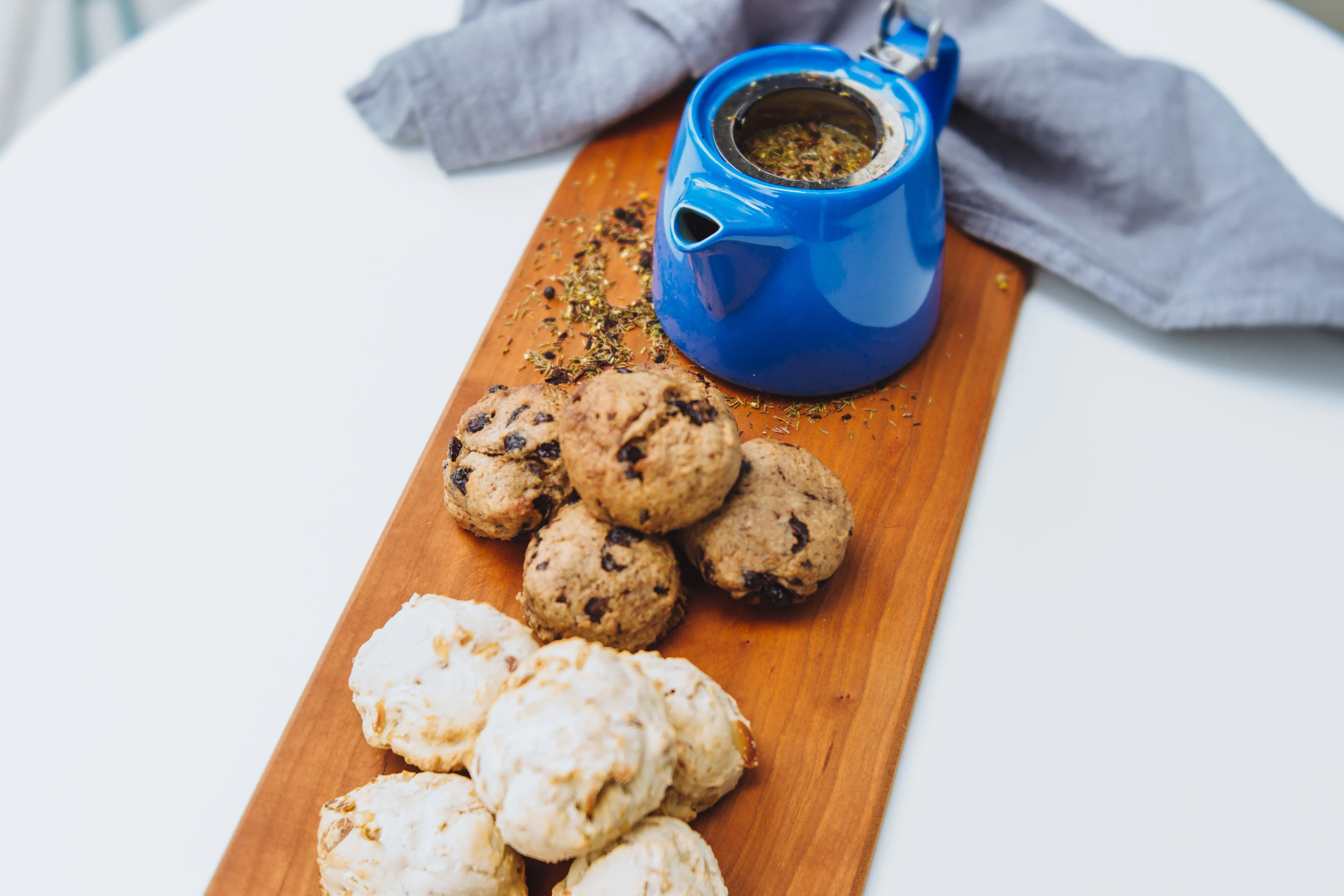 Assorted cookies with herbal tea in a blue pot on a wooden board