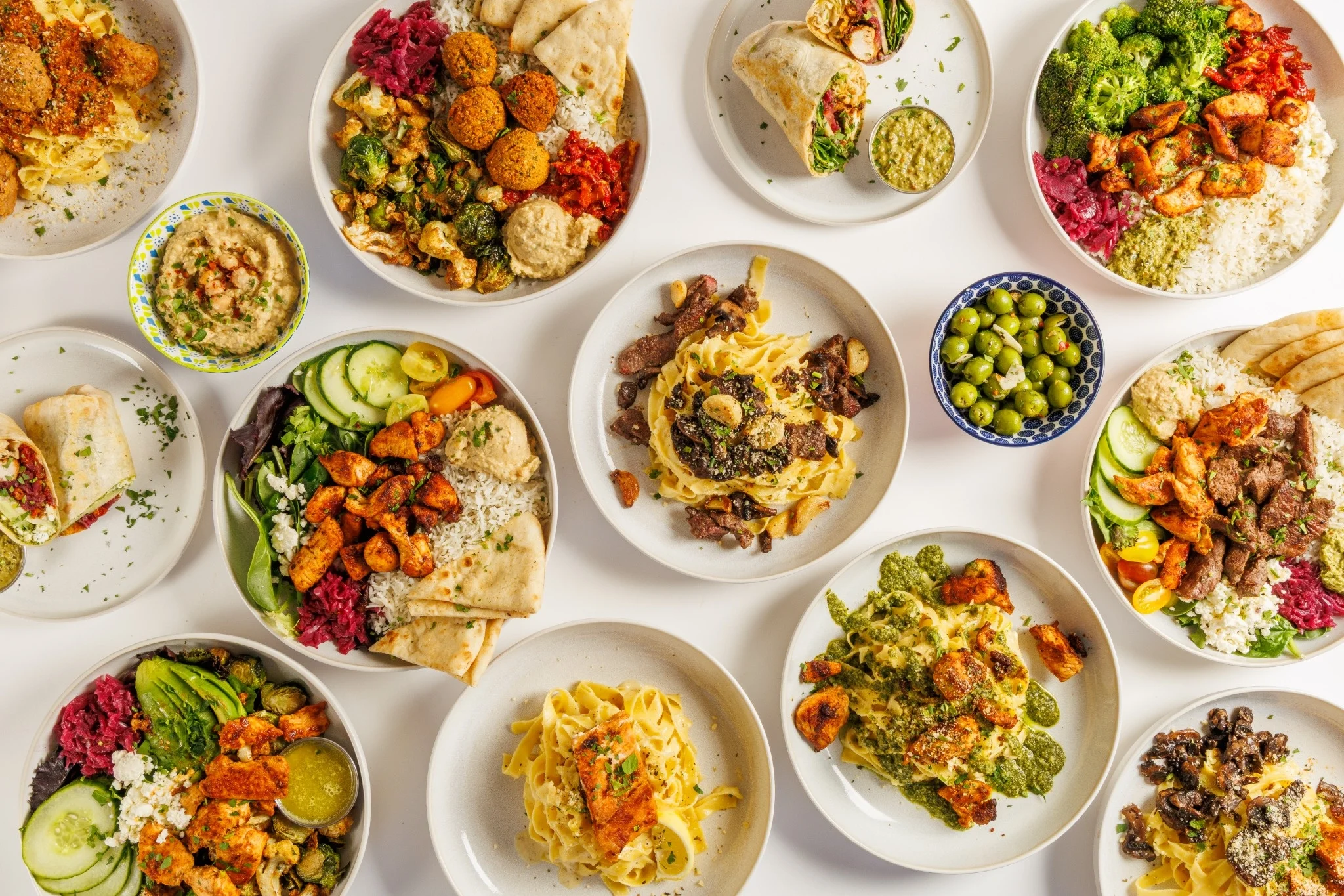 Assorted Mediterranean dishes including falafel, hummus, and grilled meats on plates