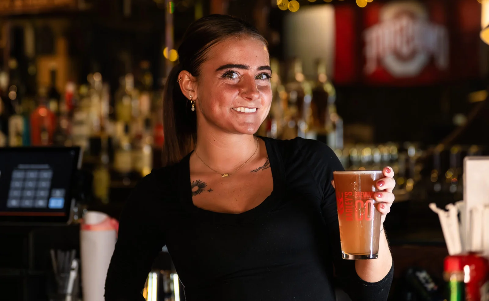 Bartender staff at Barley's smiling and serving drinks in a lively bar setting.