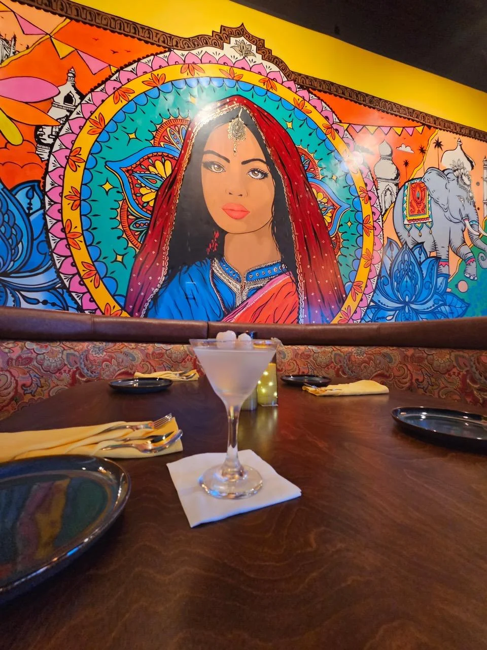 Vibrant restaurant interior with colorful mural and cocktail