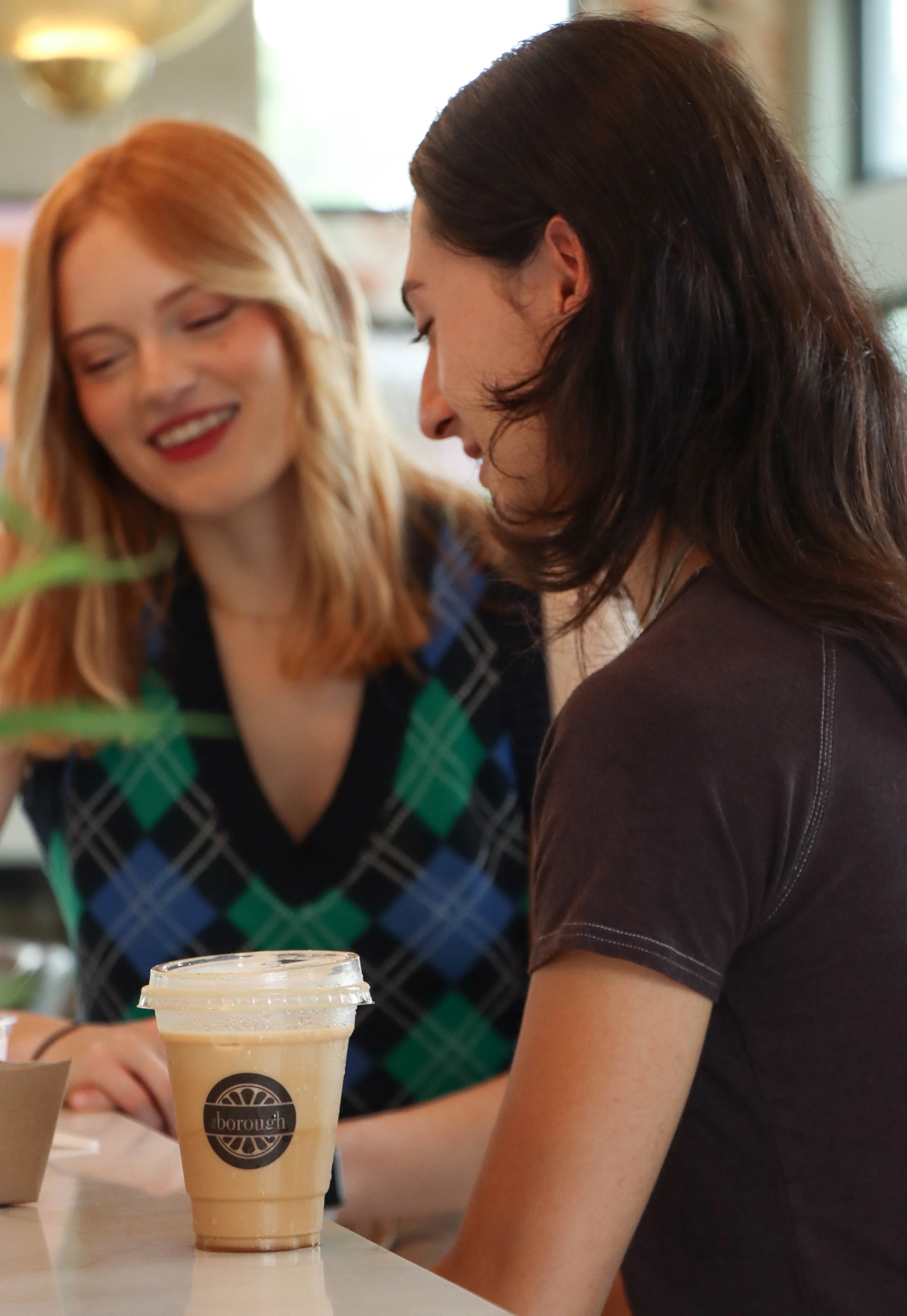 Two People Smiling over a cup of Coffee with The Borough Logo
