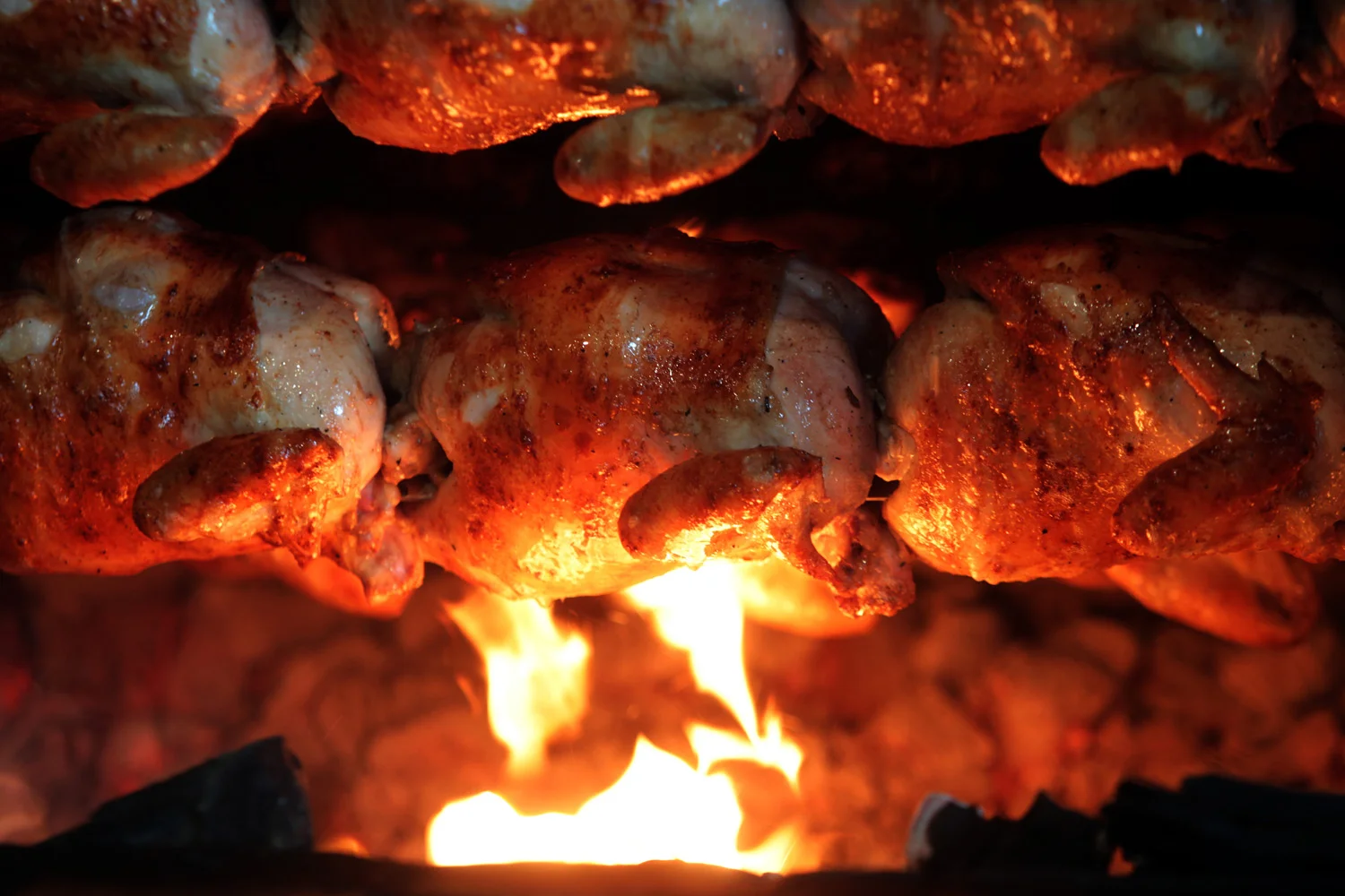 Roasting chickens over an open flame, showcasing a delicious cooking method.