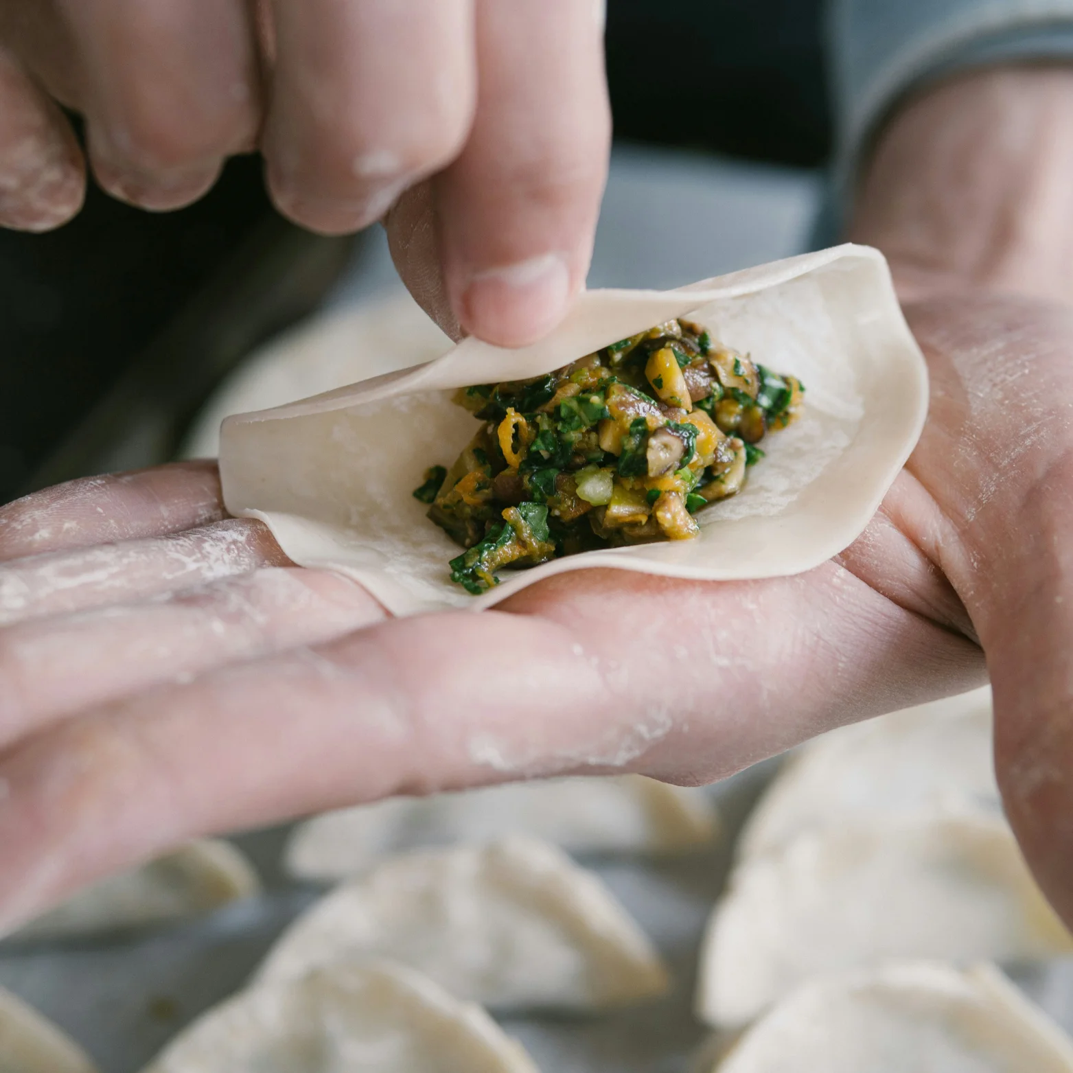 Handmade dumpling being filled with savory mixture