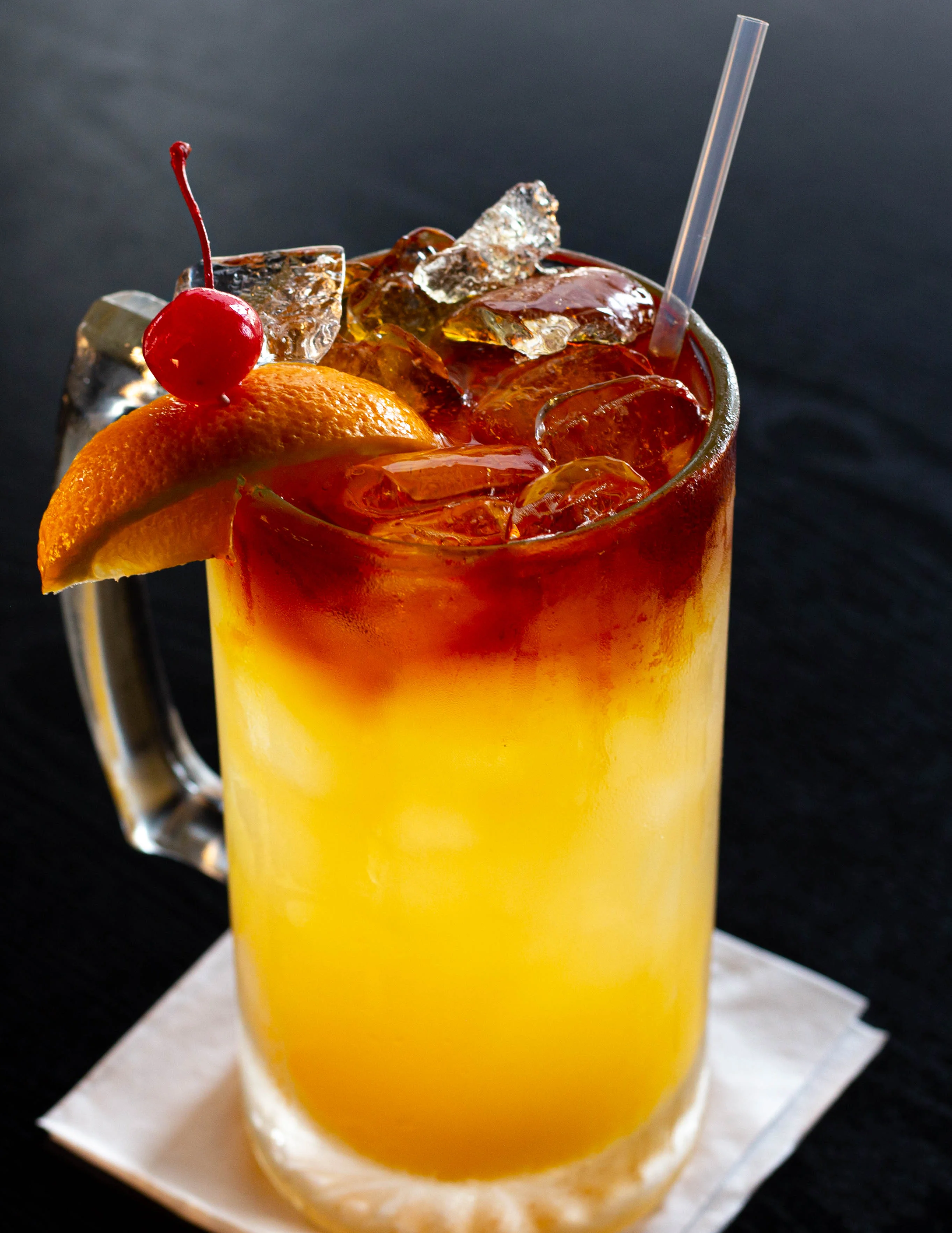 A vibrant purple drink served in a tall glass, garnished with a slice of lime and a straw.