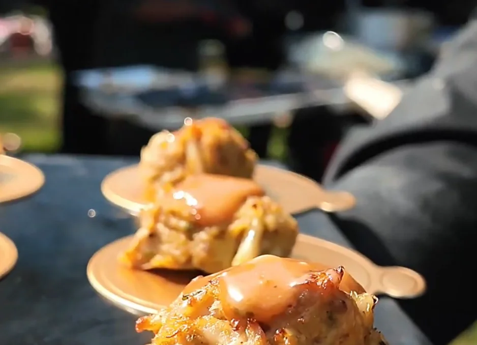Crab cakes with sauce on golden plates at an outdoor event