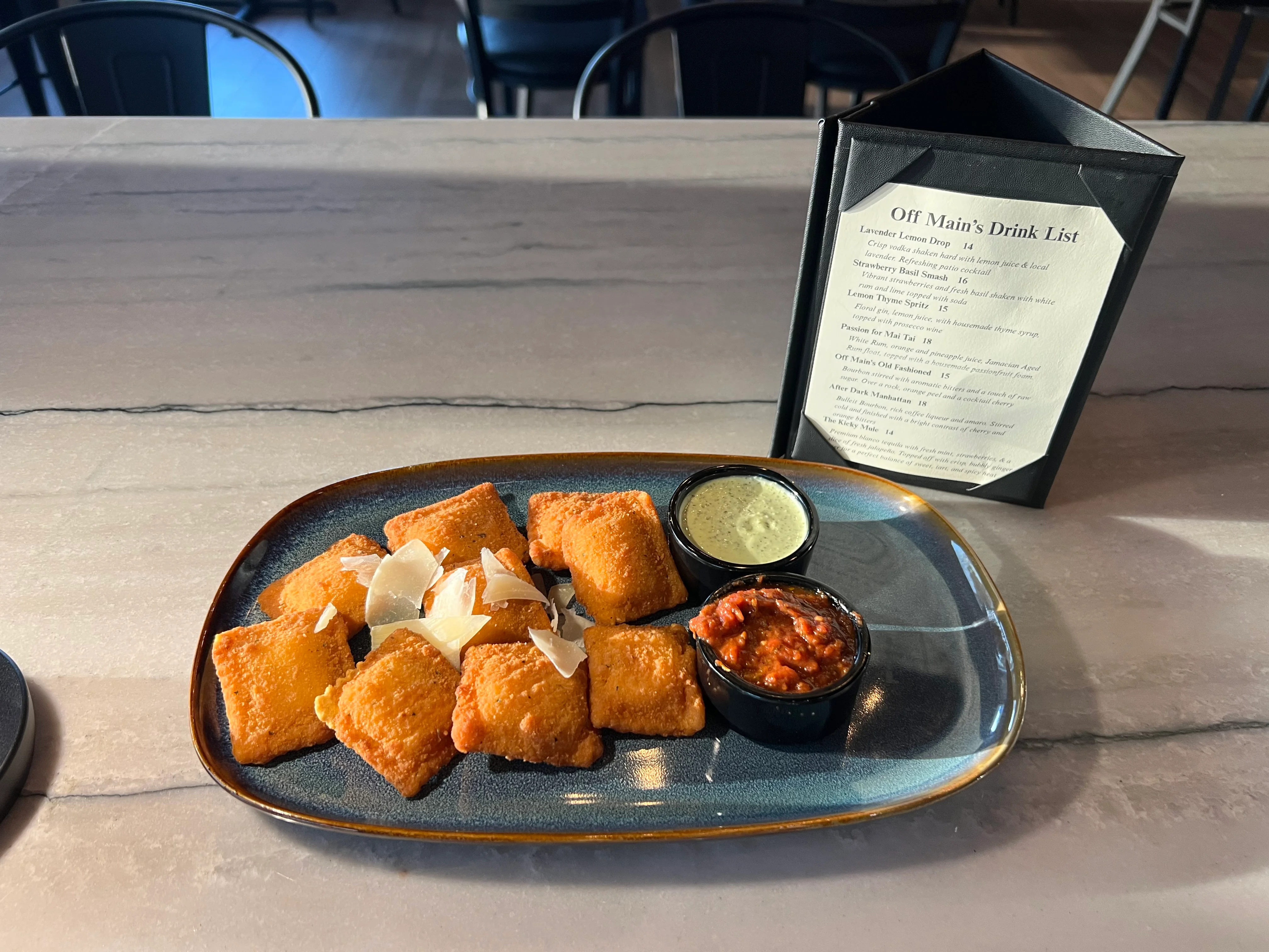 A plate of soft pretzels sprinkled with coarse salt, served with a creamy dipping sauce in a glass bowl.