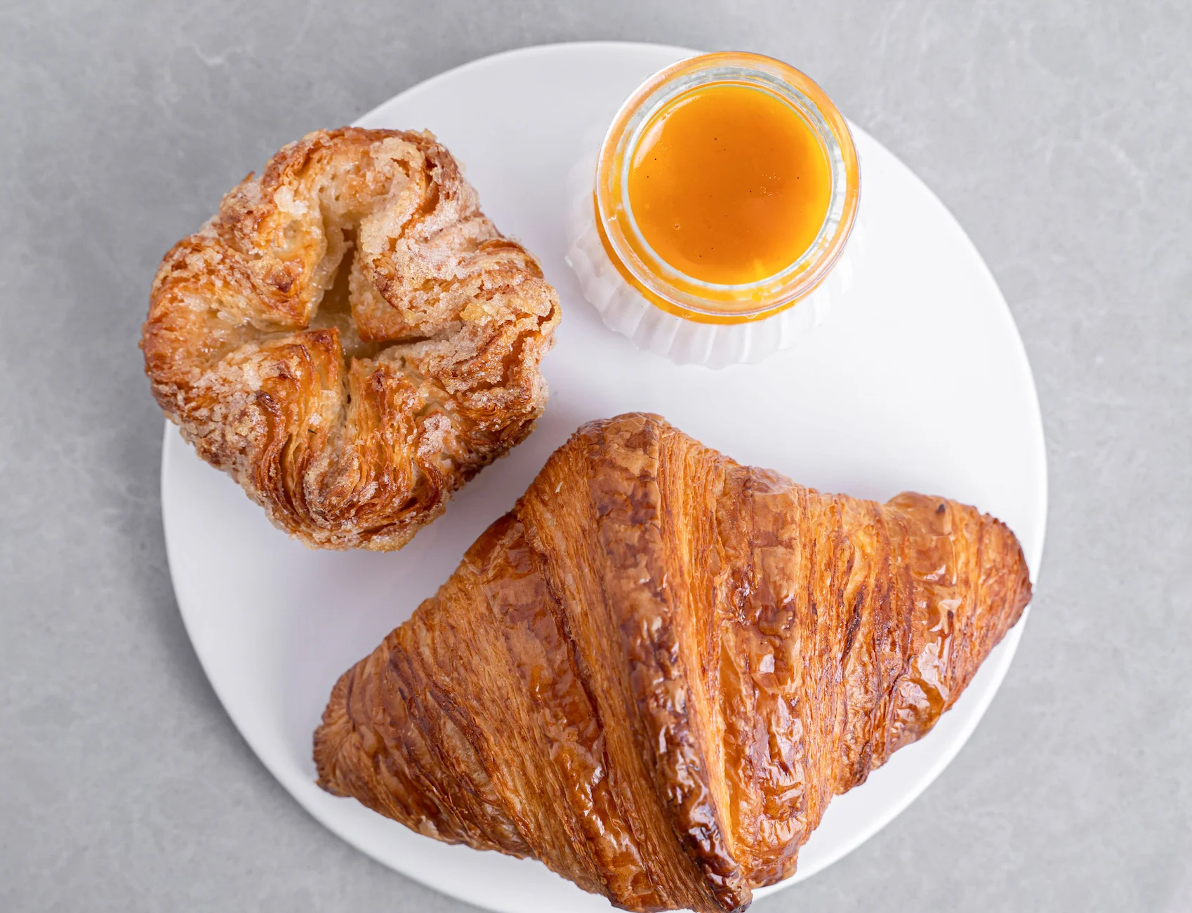 Freshly baked croissants with honey on a white plate