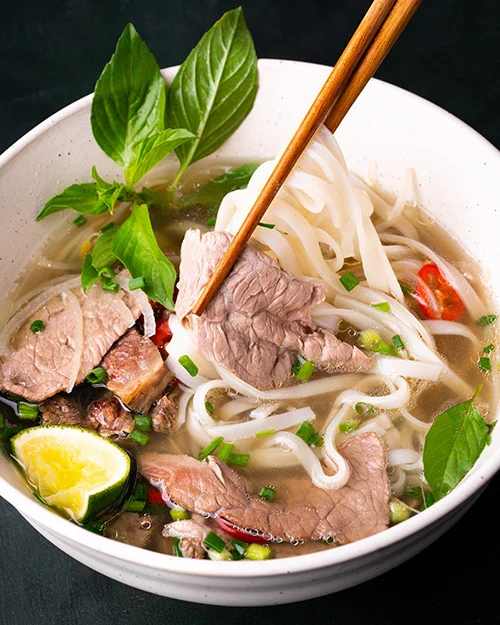 Bowl of Vietnamese pho with beef and fresh herbs