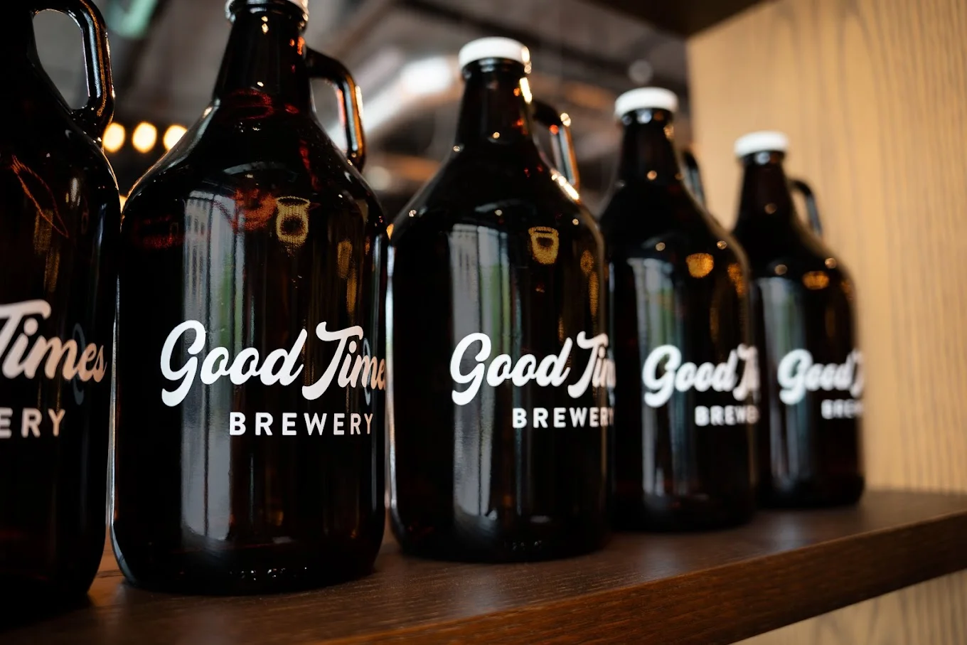 Collection of brewery growlers on a wooden shelf