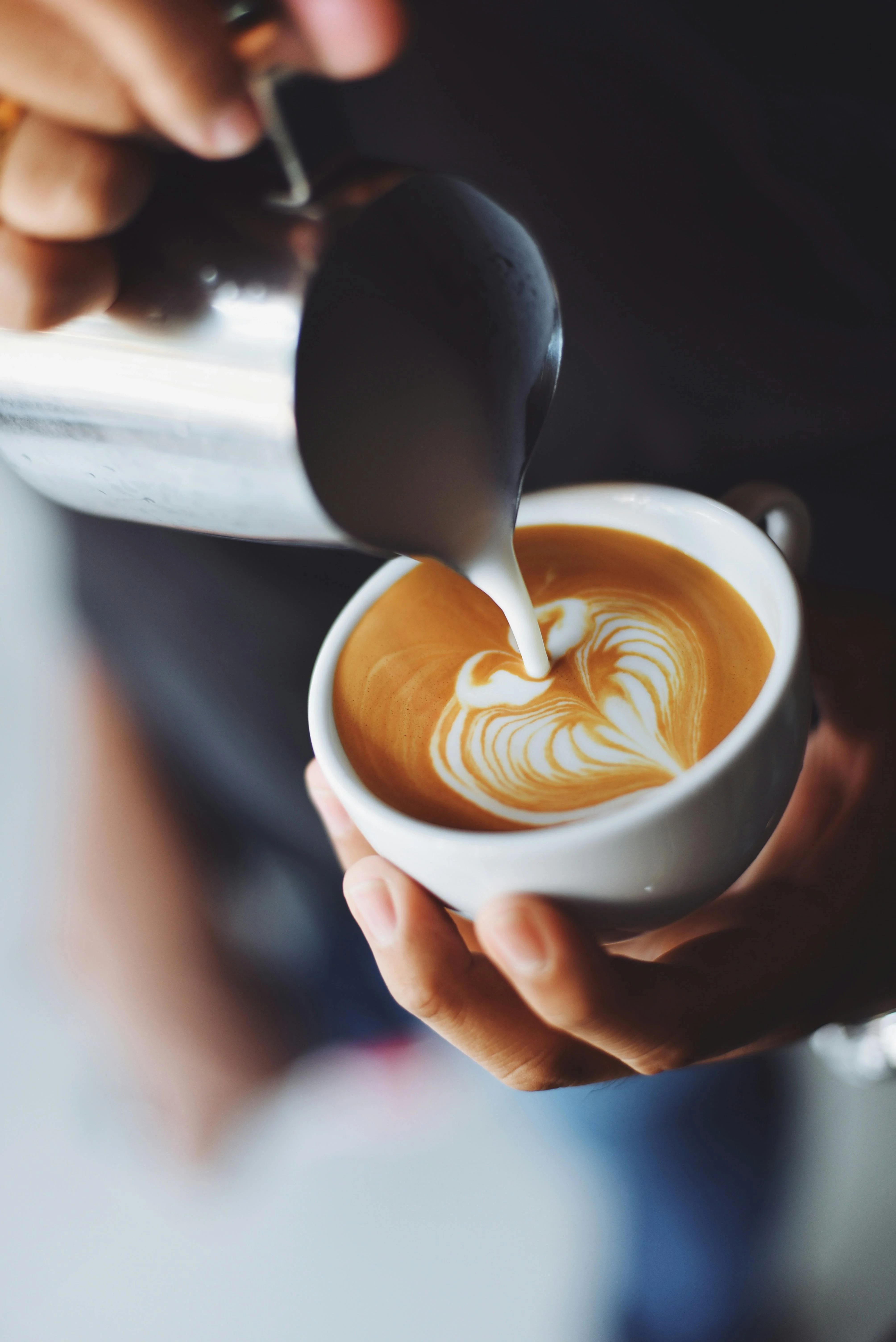 Barista pouring latte art into a cup of coffee