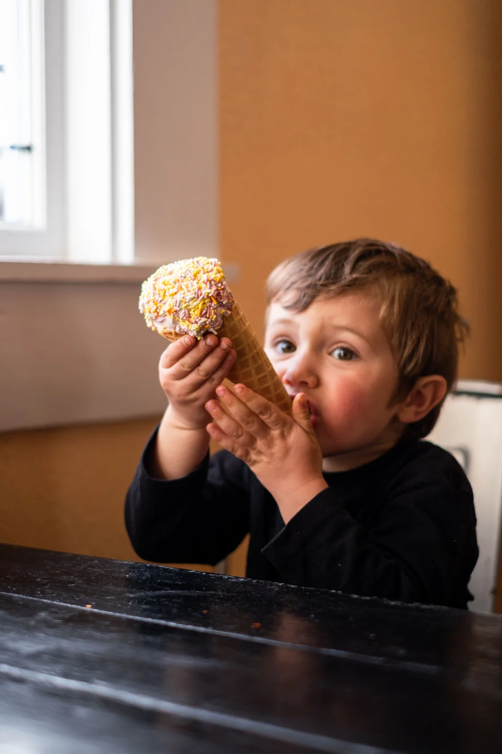 Little boy eating locally made Cowlick's ice cream in a waffle cone at Frankie's Pizza & Ice Cream in Mendocino, California