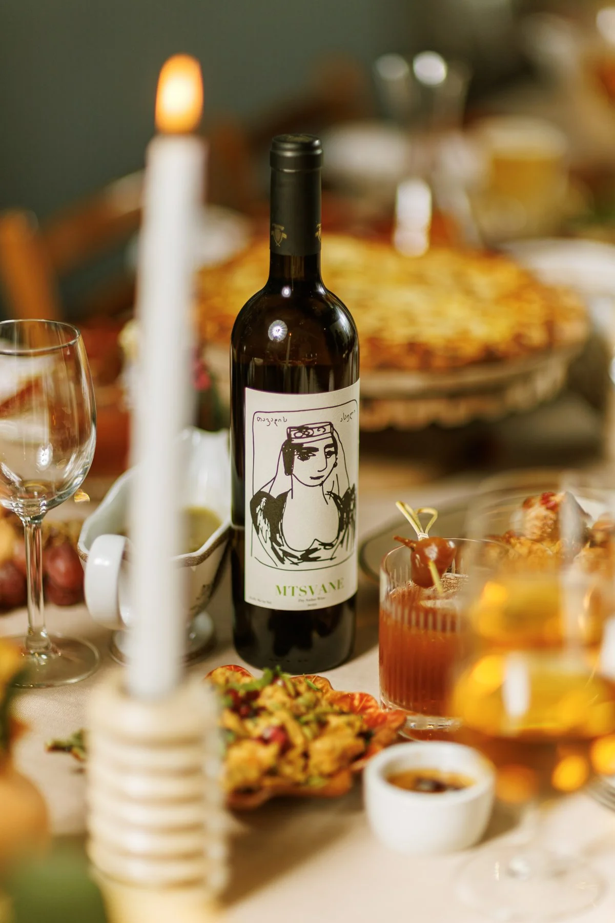 Glass of amber wine beside a bottle at a candlelit table