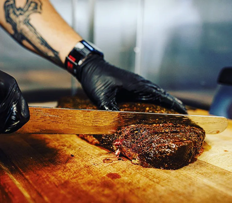 Slicing smoked brisket on a wooden cutting board