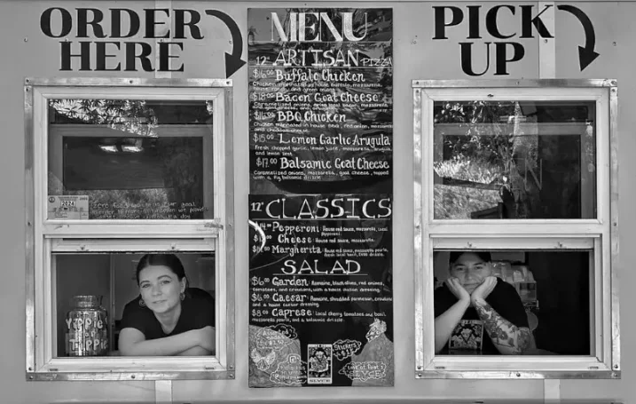 Food truck menu with artisan pizza options and staff at service windows