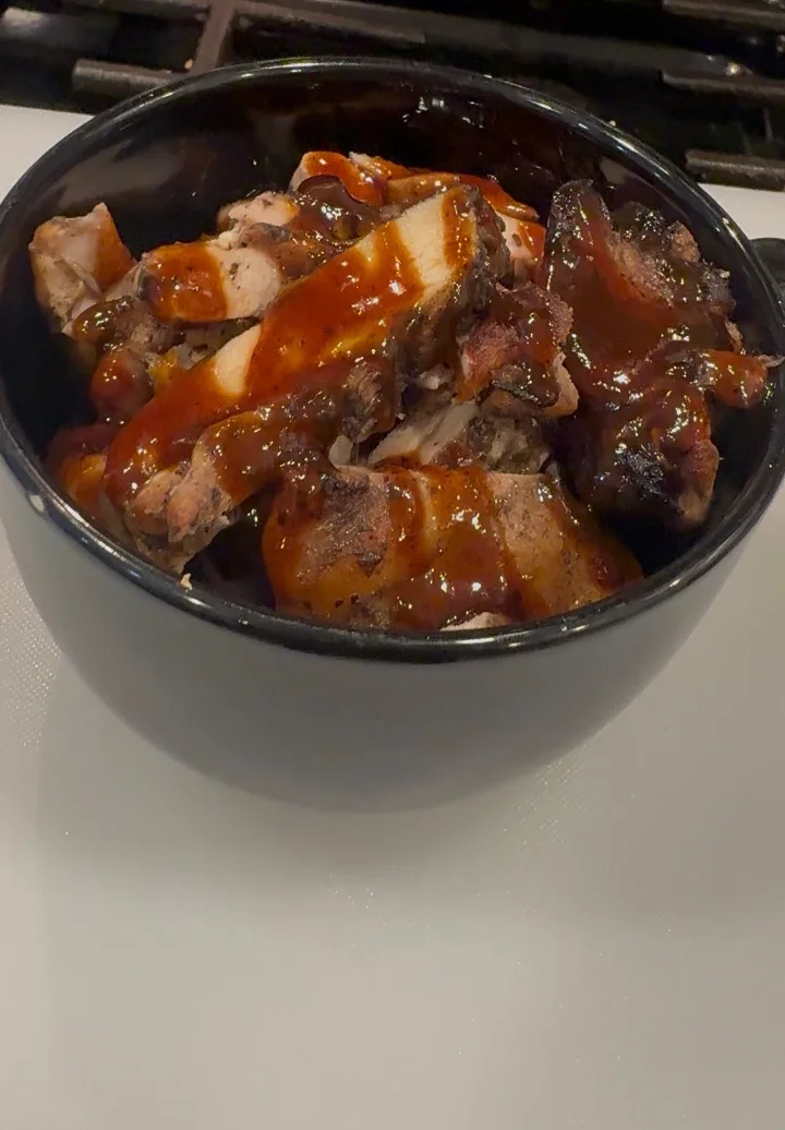 A bowl filled with BBQ smoked meat pieces covered in a rich barbecue sauce.