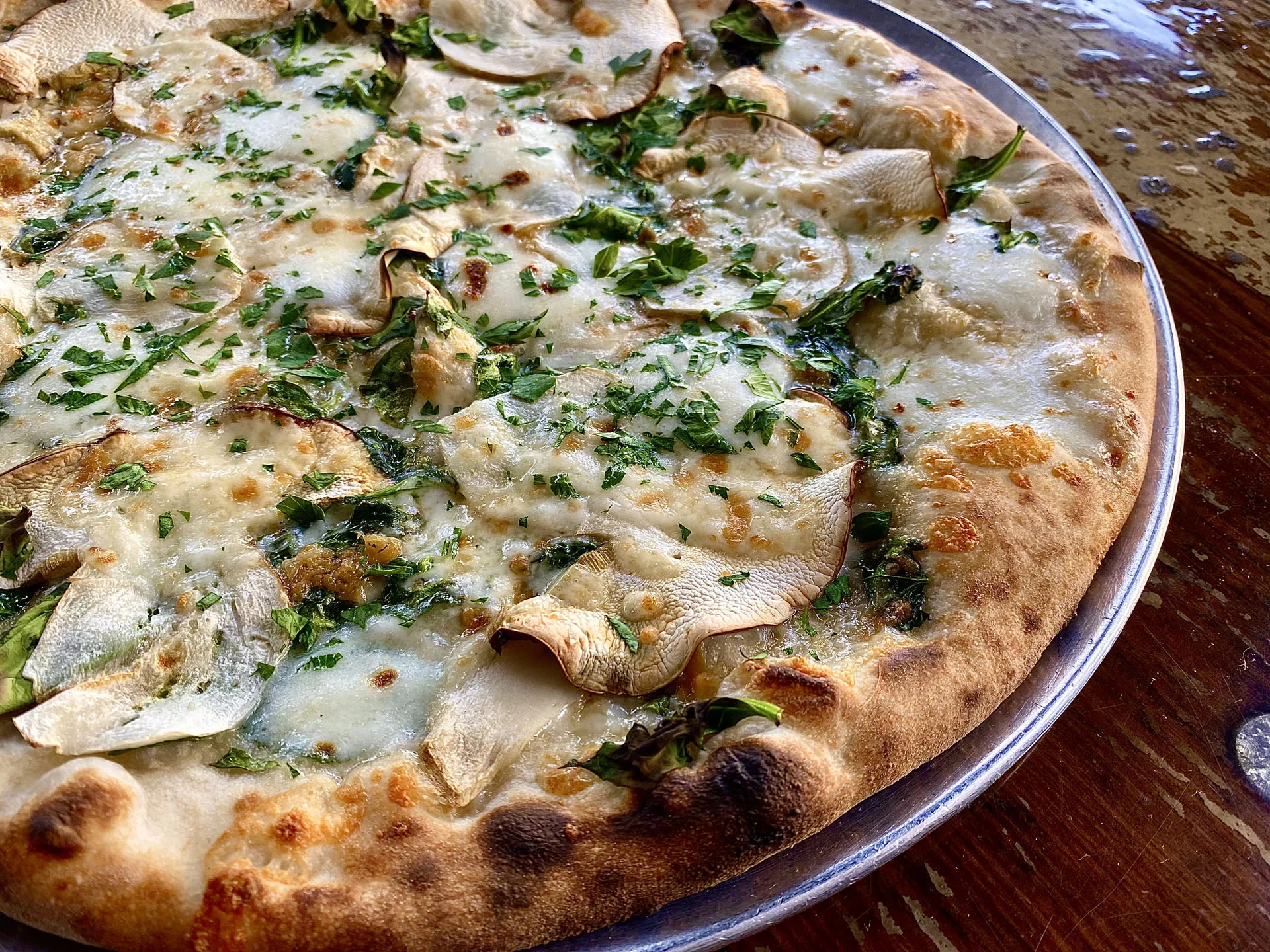 White pizza topped with fresh herbs and mushrooms