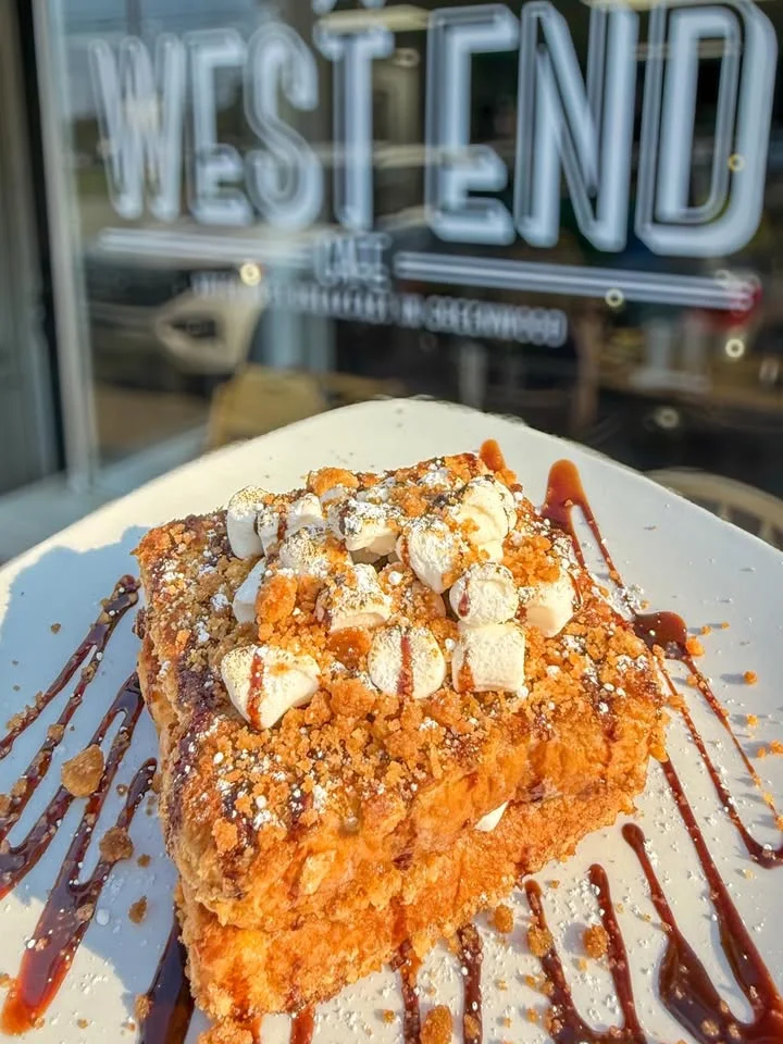 A delicious dessert consisting of two layers of sweet bread topped with whipped cream, cake crumbs, and drizzled with chocolate sauce.