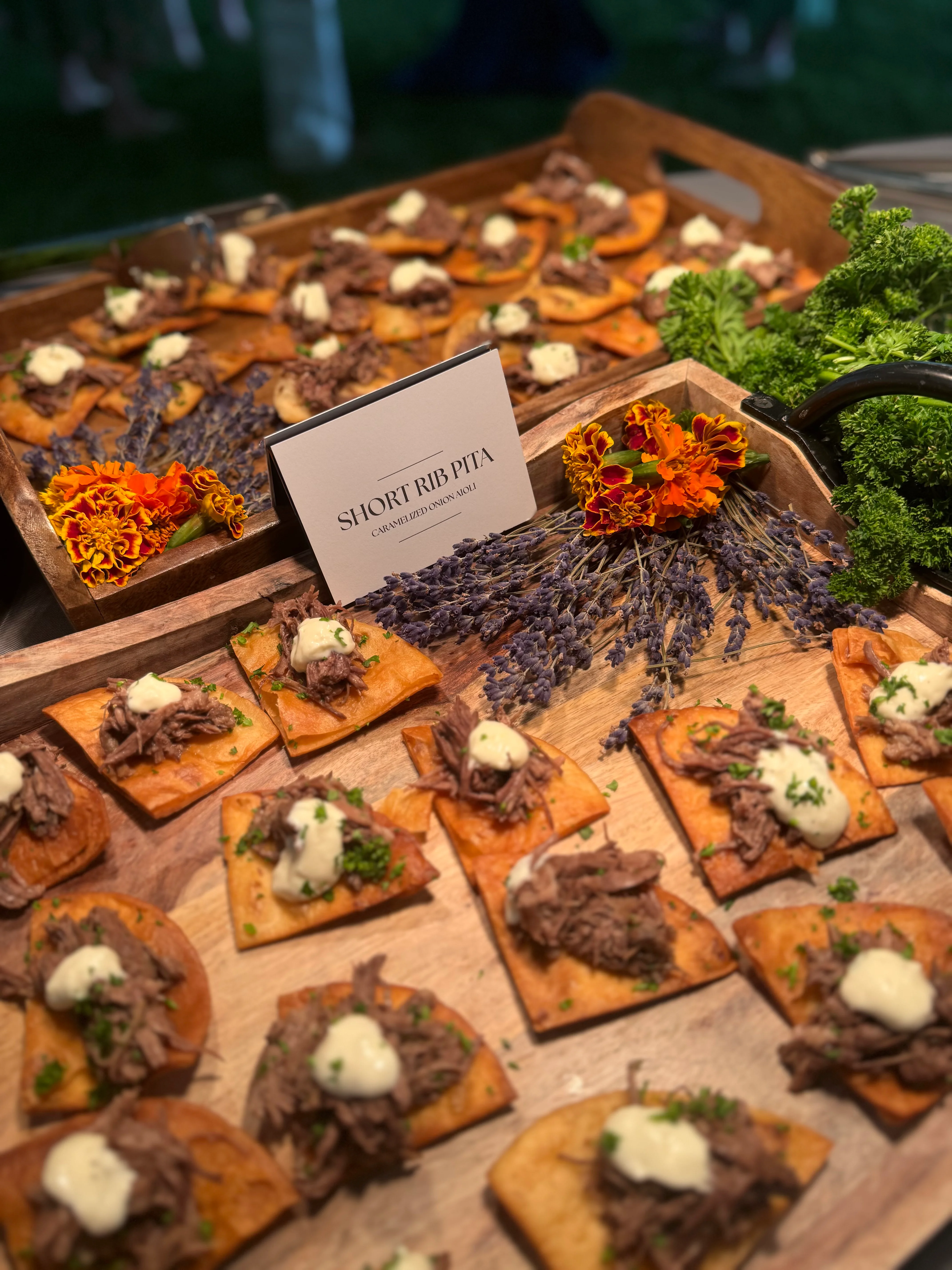 Short rib pita appetizers with garnishes on a wooden platter.