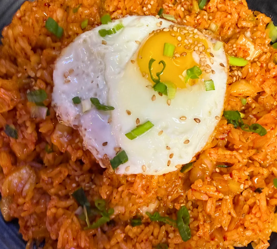 Fried rice topped with a sunny-side-up egg and green onions.