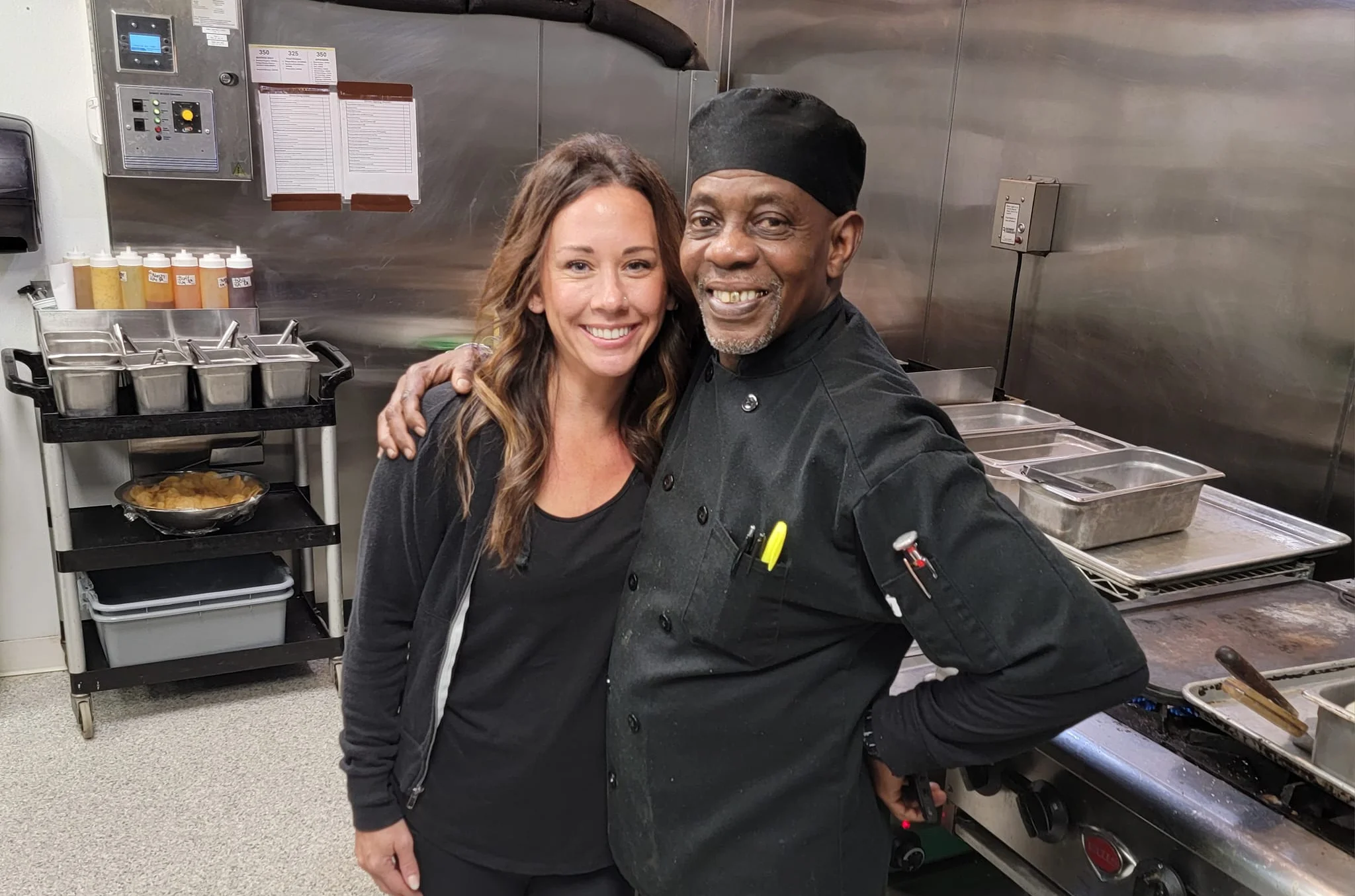 Chefs smiling together in a bustling restaurant kitchen