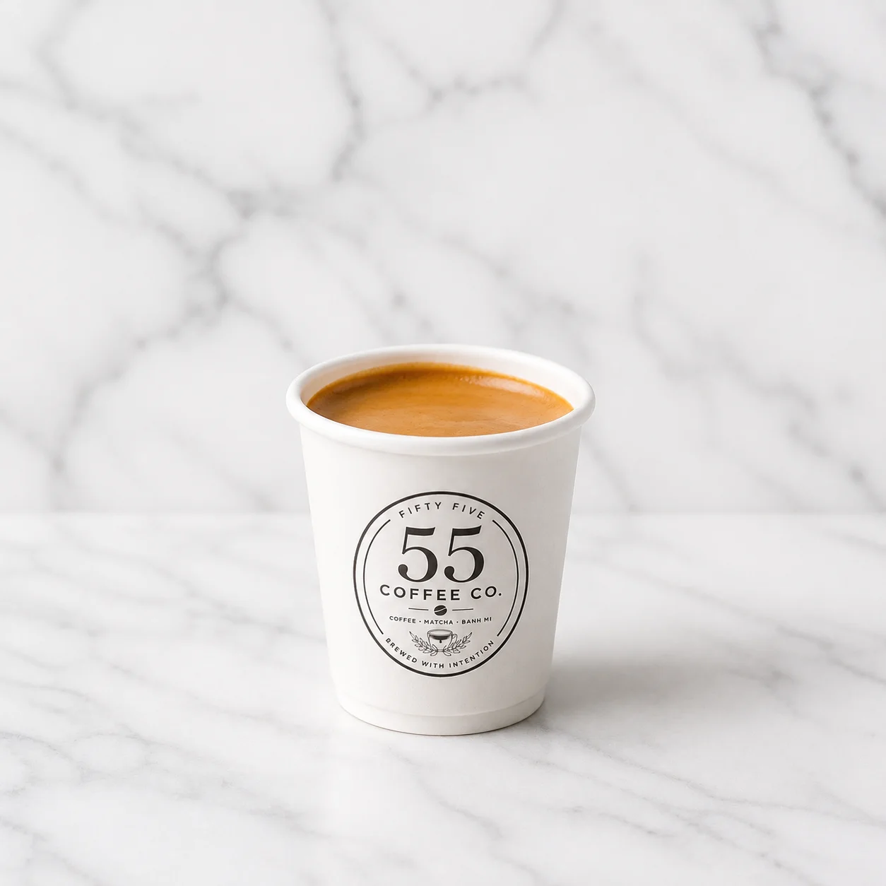 A hot espresso served in a simple white cup, showcasing rich brown coffee inside.